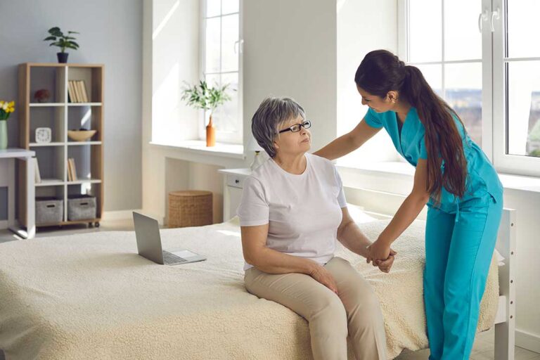 A senior resident arranging personal belongings in a cozy, sunlit room with a caregiver nearby.