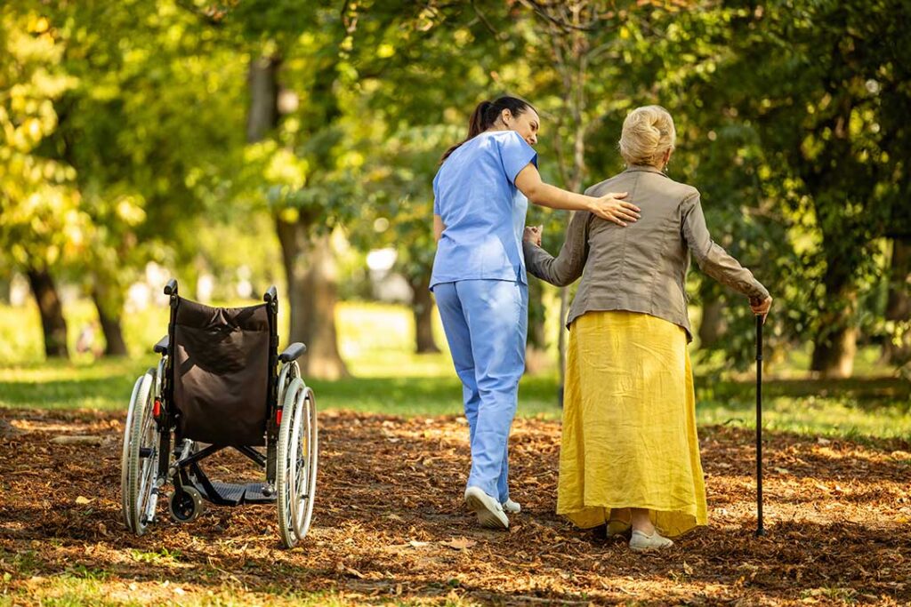 Care staff review emergency supplies and resident records beside a wheelchair in an assisted living hallway.